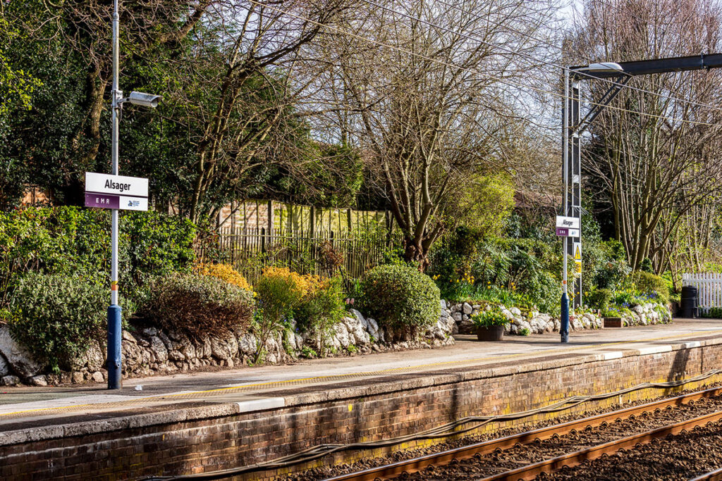 A photo of the platform at Alsager railway station. There is a rockery full of plants and flowers.