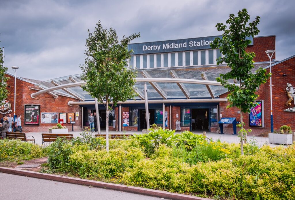 Outside Derby railway station are small gardens full of bushes and trees, along with benches.