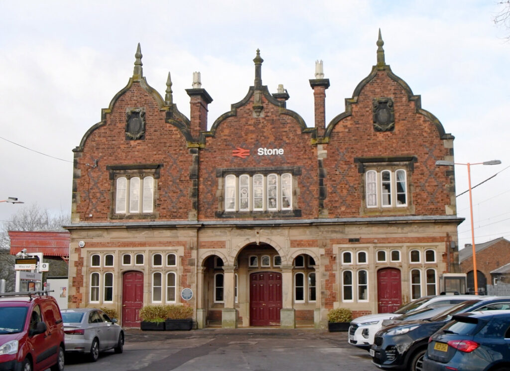 The facade of Stone Railway Station, a distinct stone and brick building with three spires.
