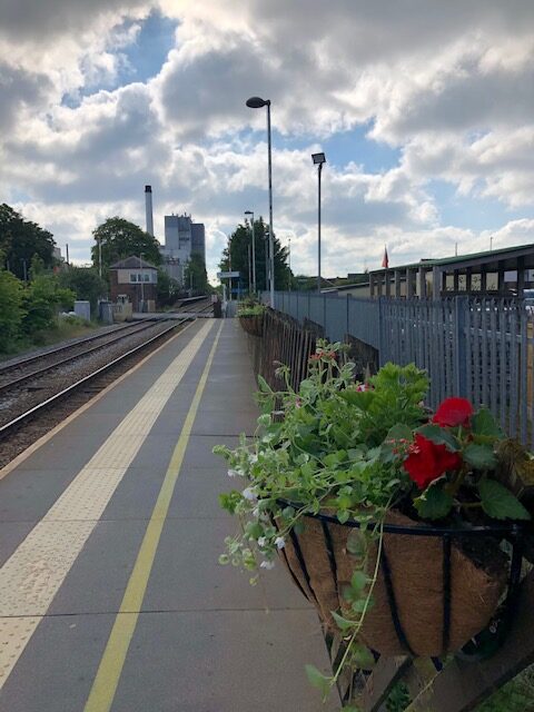 A basket of flowers adorns the long platform at Tutbury & Hatton railway station, which stretches into the distance.