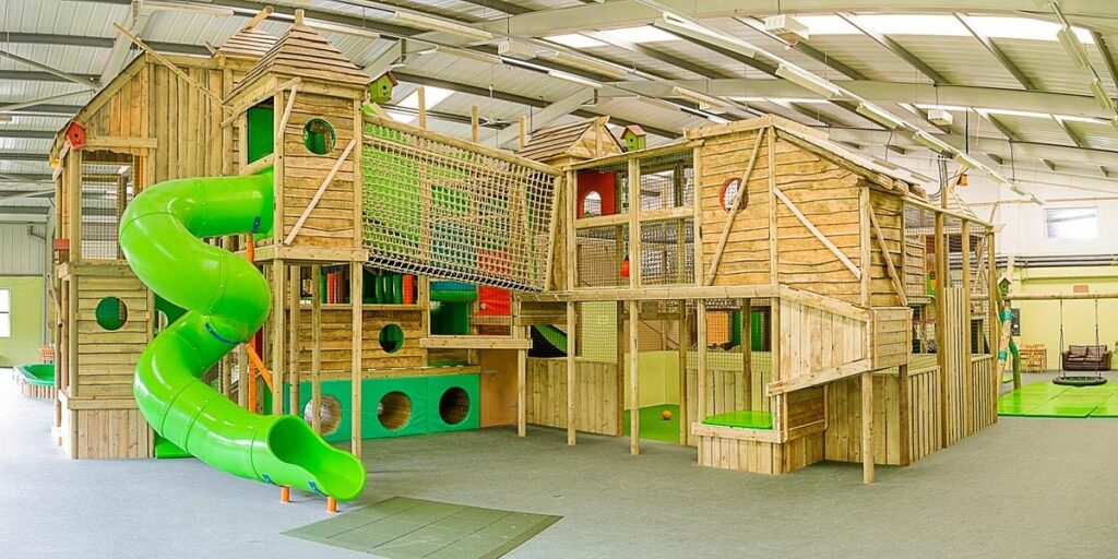 An image of come into play - a giant indoor treehouse complete with nets, soft play areas and slides.