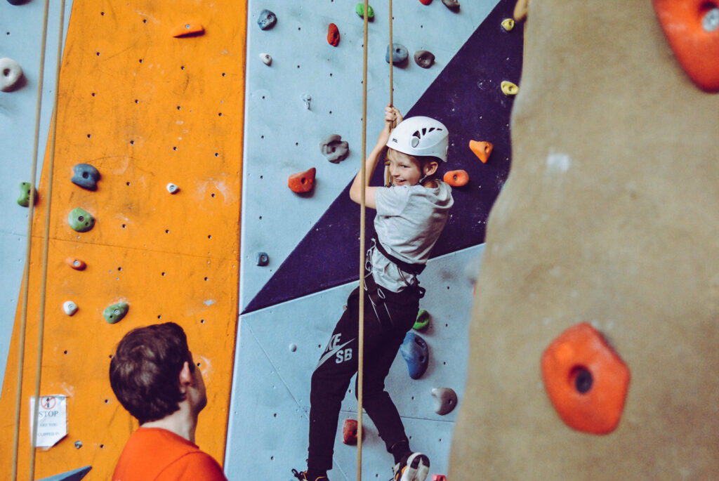 A child hanging on a rope enjoying climbing.