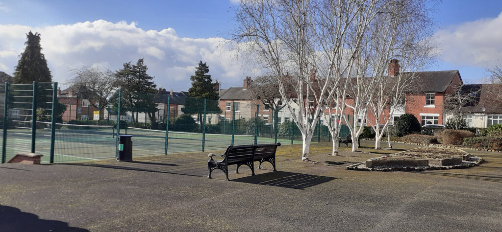 An image of part of Stonefield park, featuring tennis courts and benches.