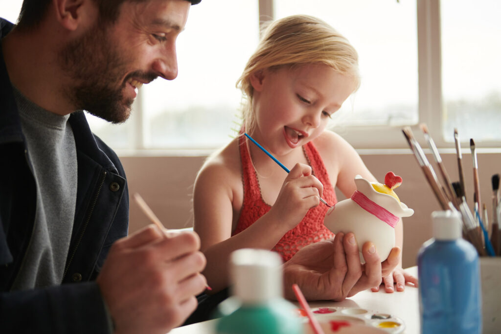 A child and parent painting pottery at World of Wedgwood