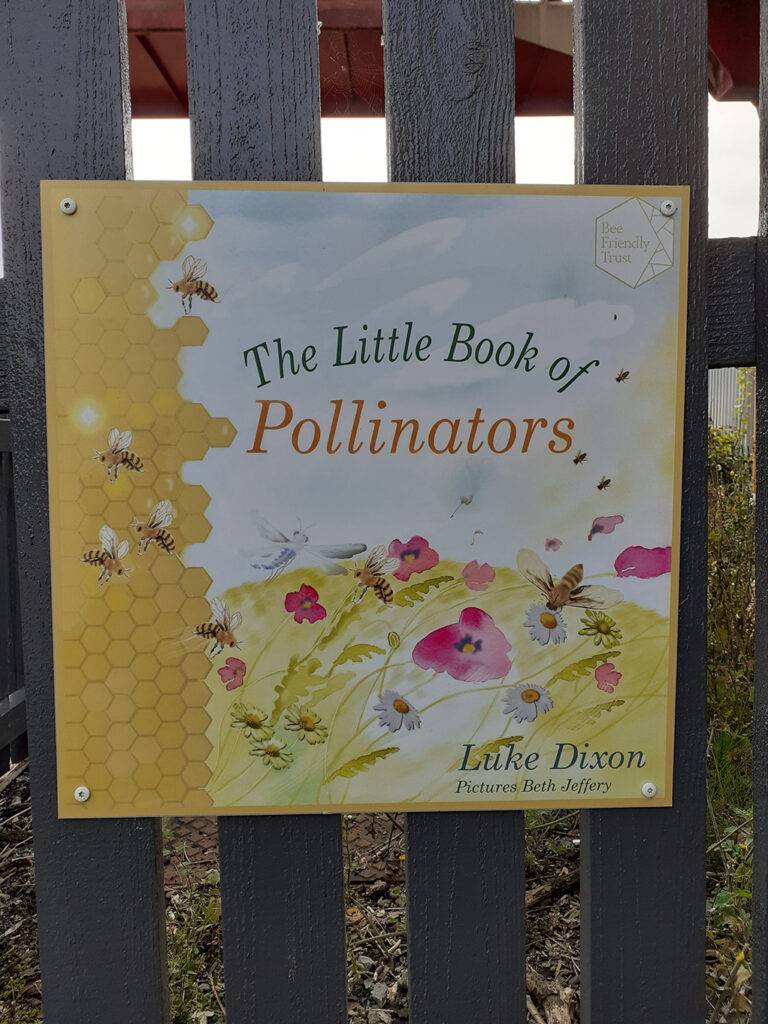 Picture of the front page panel of Little Book of Pollinators by Luke Dixon. It is displayed as a metal panel on the fence at Stone Station
