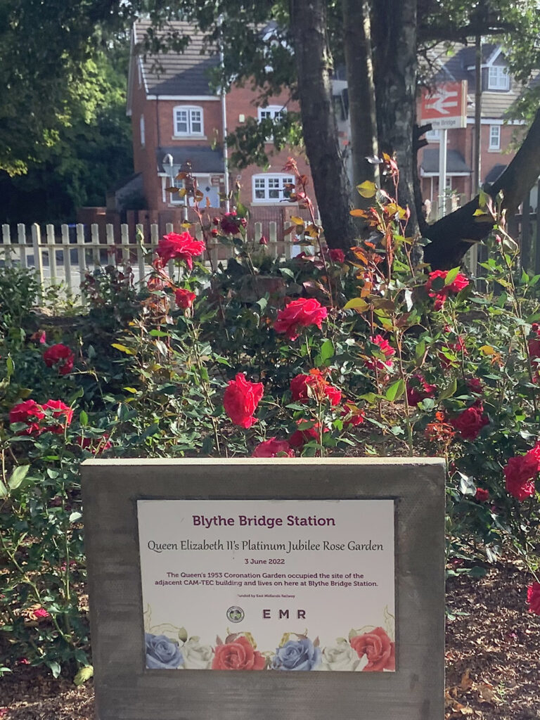 Picture of a commemorative plaque for the Queen's Platinum Jubilee placed in front of the garden bed outside the Blythe Bridge station car park.