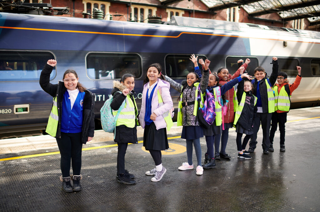 Picture of the a group of Year 4 students in front of the platform at Stoke Station ready to catch a train.
