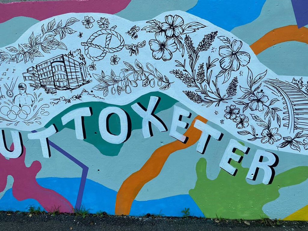 Picture showing the new mural at Uttoxeter station at Platform 1. It has the word "Uttoxeter" across it underneath a collage of places in the local area as chosen by local residents.