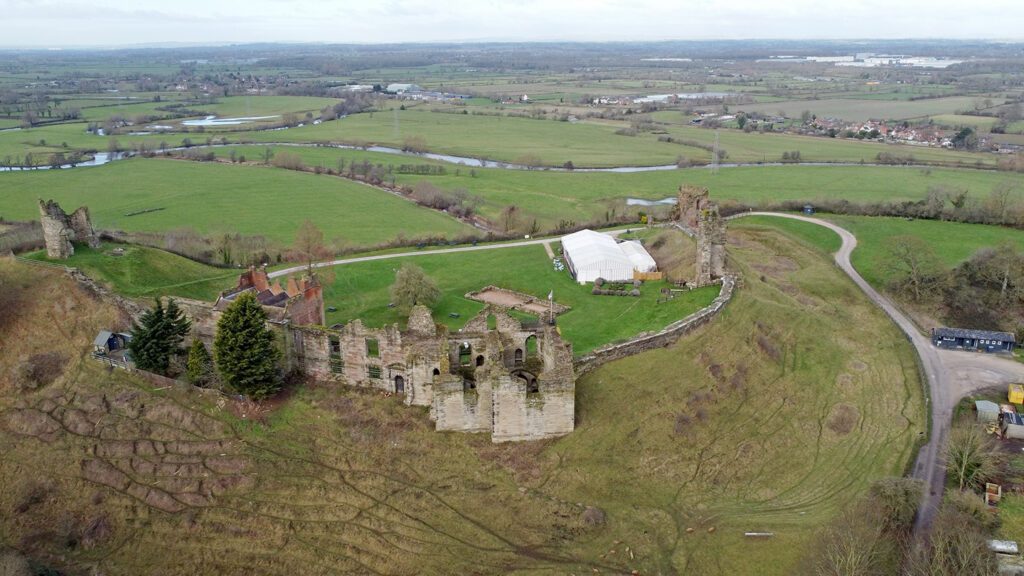 Aerial shot of Tutbury Castle from behind. The river can be seen in the far background of the image